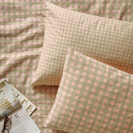 Harriet Gingham reversible cotton pillowcase pair in pink and green, shown on matching gingham bedding with textured seersucker check pattern.