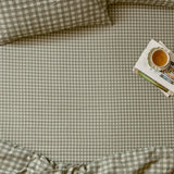 Harriet Gingham Check Cotton Fitted Sheet in baygreen/mist on a bed, showing the sage-and-cream check pattern with matching pillowcases, styled with a tray of books and tea.