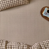 Harriet Gingham Check Cotton Fitted Sheet in buttermilk and chocolate, shown on a bed with matching pillowcase and duvet, styled beside a wooden tray with coffee and books.