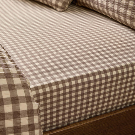 Harriet Gingham Check Cotton Fitted Sheet in buttermilk and chocolate, fitted on a mattress with matching pillowcases, showing the small woven check pattern.