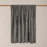 Harrow Plain Polyester Throw in charcoal, a flannel fleece throw with a smooth brushed grey finish, draped over a wooden rail against a plain light background.
