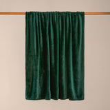 Harrow Plain Polyester Throw in emerald green, plain flannel fleece with a dense short pile, draped over a wooden pole against a plain neutral background.
