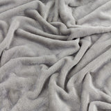 Close-up of the Harrow Plain Polyester Throw in grey, showing its soft, brushed flannel fleece texture folded into gentle waves.