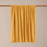 Harrow Plain Polyester Throw in ochre yellow, a soft flannel fleece blanket draped over a rod against a neutral background.
