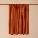 Harrow Plain Polyester Throw in rust orange, draped over a rail to show its flannel fleece texture, against a plain neutral background.