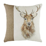 Square cream linen cushion with a hand-painted watercolour stag design beside a hessian-effect panel, joined by contrast stitching, on a plain white background.