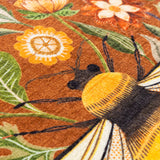 Close-up of the Hawthorn printed velvet chenille cushion in ginger, showing a bumblebee's head and thorax amid orange, ochre and green floral detail.