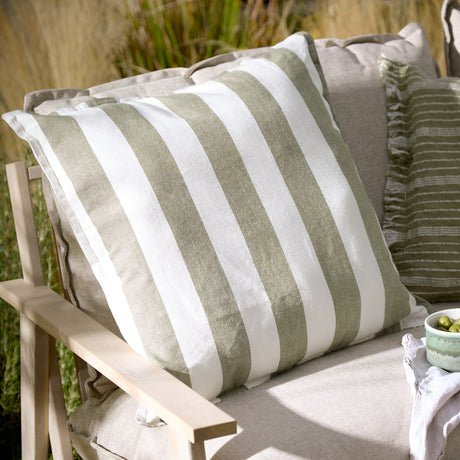 Hayle Reversible Cotton Cushion in Lichen, square 50x50cm with bold green and white stripes, shown on an outdoor sofa alongside neutral and striped cushions.