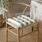 Hayle Reversible Cotton Seat Pad in moss green and cream broad stripe, tied onto a wishbone-style dining chair with woven rattan seat.