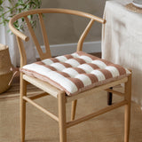 Hayle Reversible Cotton Seat Pad in pecan brown and cream broad stripe, tufted with tie fastening, shown on a wishbone-style wooden dining chair.