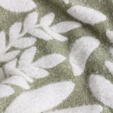 Hazel Botanical Polyester Throw in olive, close-up of the woven fabric showing a white leaf pattern on a green textured ground.