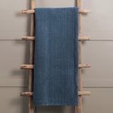 Haze Velvet Cotton Throw in Bluebell blue, quilted cotton velvet with vertical stitched texture, draped over a wooden ladder against a neutral wall.