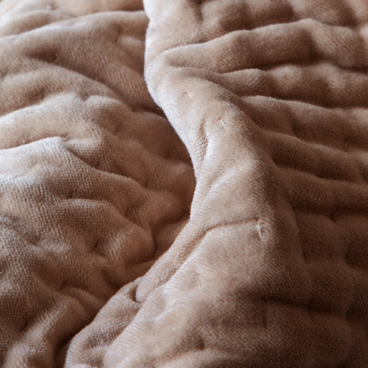 Close-up of the Haze Velvet Cotton Throw in coral-brown, showing hand-quilted velvet texture with soft folds and visible stitching rows.