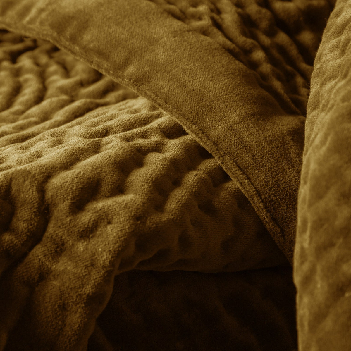 Close-up of the Haze Velvet Cotton Throw in mustard, showing hand-quilted, rippled cotton velvet texture with a folded edge and dense, short pile finish.
