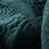 Close-up of the Haze Velvet Cotton Throw in Ocean, showing hand-quilted teal velvet with a rippled texture and a folded edge revealing a smooth reverse.