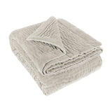 Folded Haze Velvet Cotton Throw in Quartz, a pale stone-neutral hand-quilted cotton throw with wave-like stitching, shown on a plain white background.