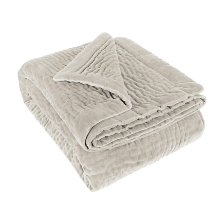 Folded Haze Velvet Cotton Throw in Quartz, a pale stone-neutral hand-quilted cotton throw with wave-like stitching, shown on a plain white background.