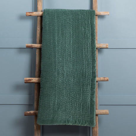 Haze Velvet Cotton Throw in seafoam green, hand-quilted velvet cotton with a textured channel pattern, draped over a wooden ladder against a pale blue-grey wall.