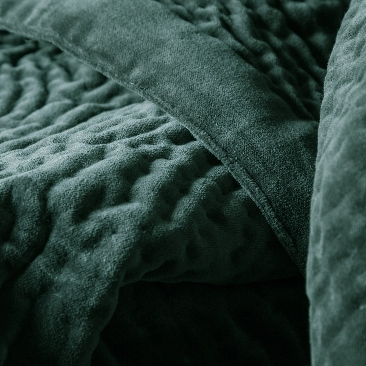 Close-up of the Haze Velvet Cotton Throw in seafoam green, showing hand-quilted cotton velvet with a bubbled texture and folded seam detail.