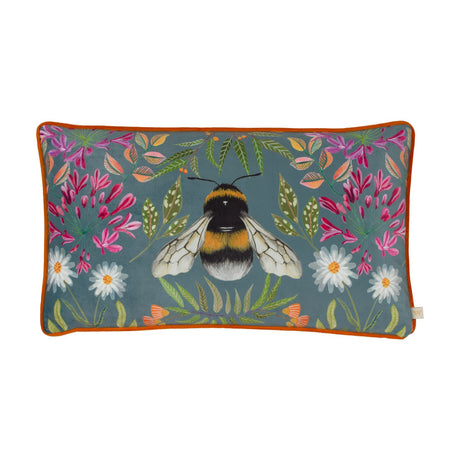 House of Bloom rectangular velvet cushion featuring a central bee design with pink, magenta, white and orange florals and green foliage on blue-grey, orange piped edge, white background.
