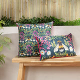 House of Bloom Animal Polyester Cushion in navy with bee and floral print, shown in square and rectangular sizes with pink piping on a wooden bench outdoors.