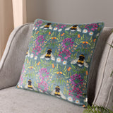 House of Bloom Floral Velvet Cushion in blue-grey, printed with bumble bees and pink florals, shown on a grey armchair.