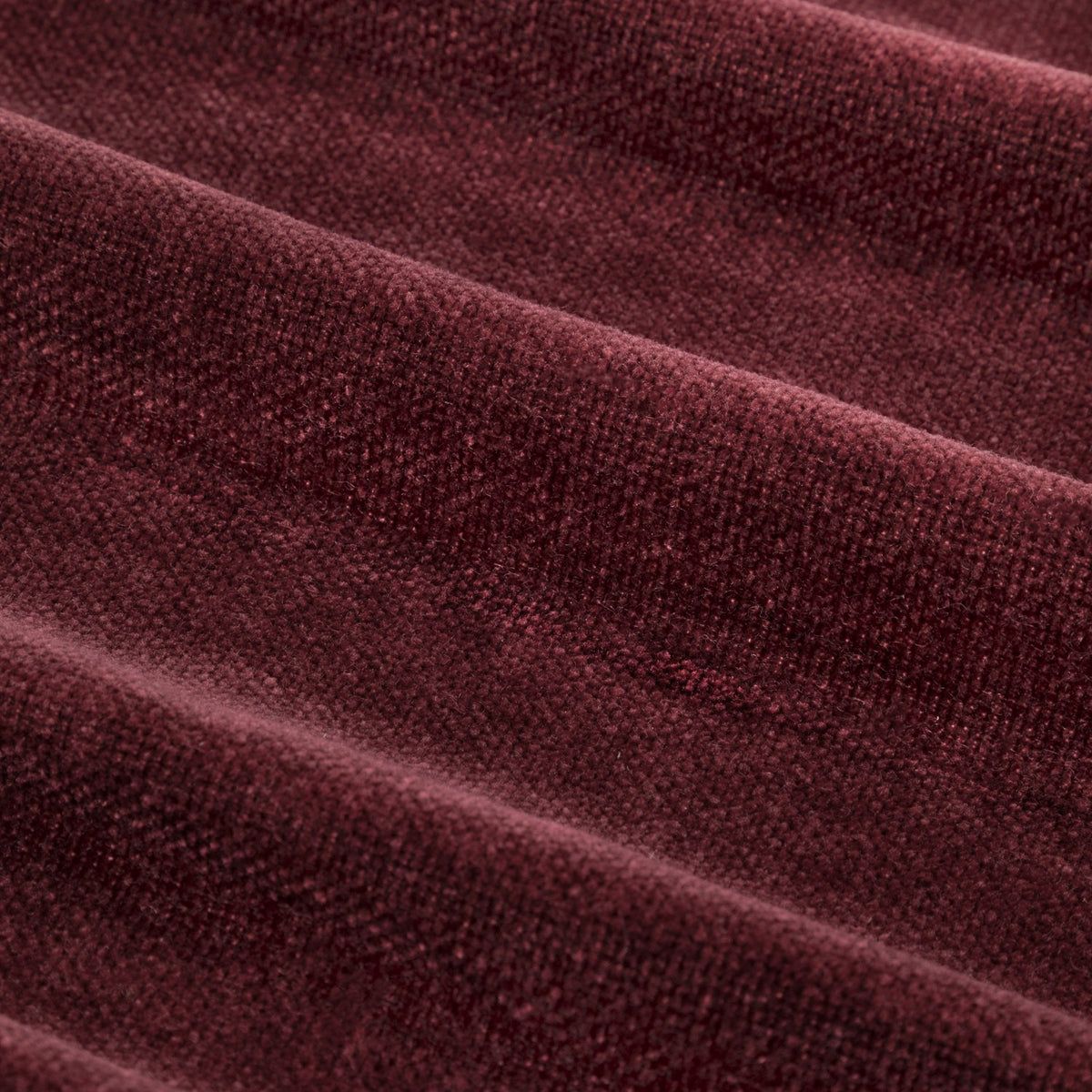 Close-up of heavy chenille velvet eyelet curtain fabric in deep beetroot red, showing soft mottled pile and rounded folds.