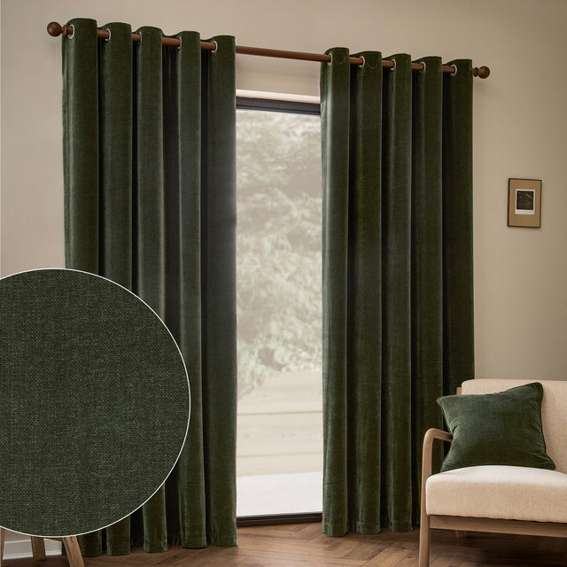 Heavy chenille velvet eyelet curtains in lichen green hanging on a wooden pole in a living room, with a fabric close-up inset and beige armchair nearby.