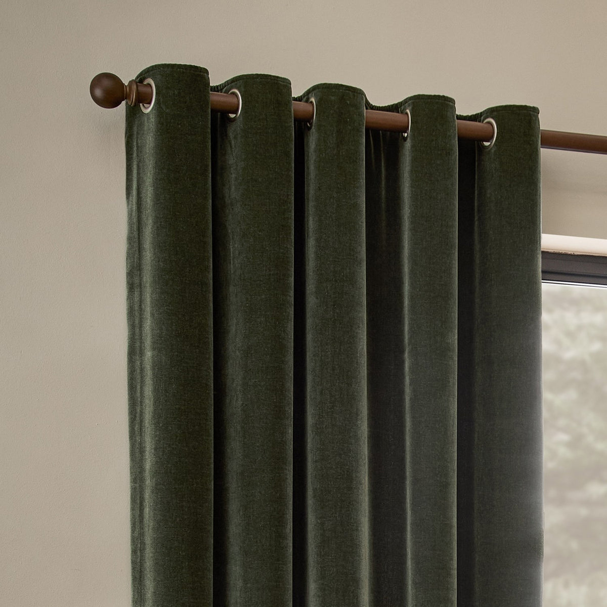 Heavy Chenille Velvet Fully Lined Eyelet Curtains in lichen green, hung on a wooden pole with metal eyelets, forming rounded folds against a neutral wall.