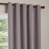 Heavy chenille velvet eyelet curtains in muted mauve, fully lined, hung on a brown rod near a window in a light-toned room.