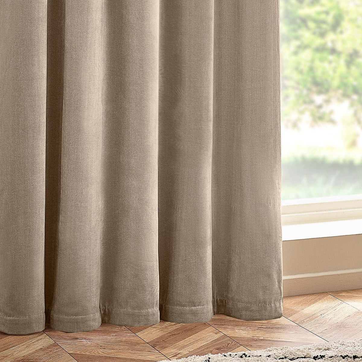 Heavy chenille velvet eyelet curtains in natural beige, shown in soft folds against a window with wooden flooring.