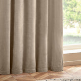 Heavy chenille velvet eyelet curtains in natural beige, shown in soft folds against a window with wooden flooring.