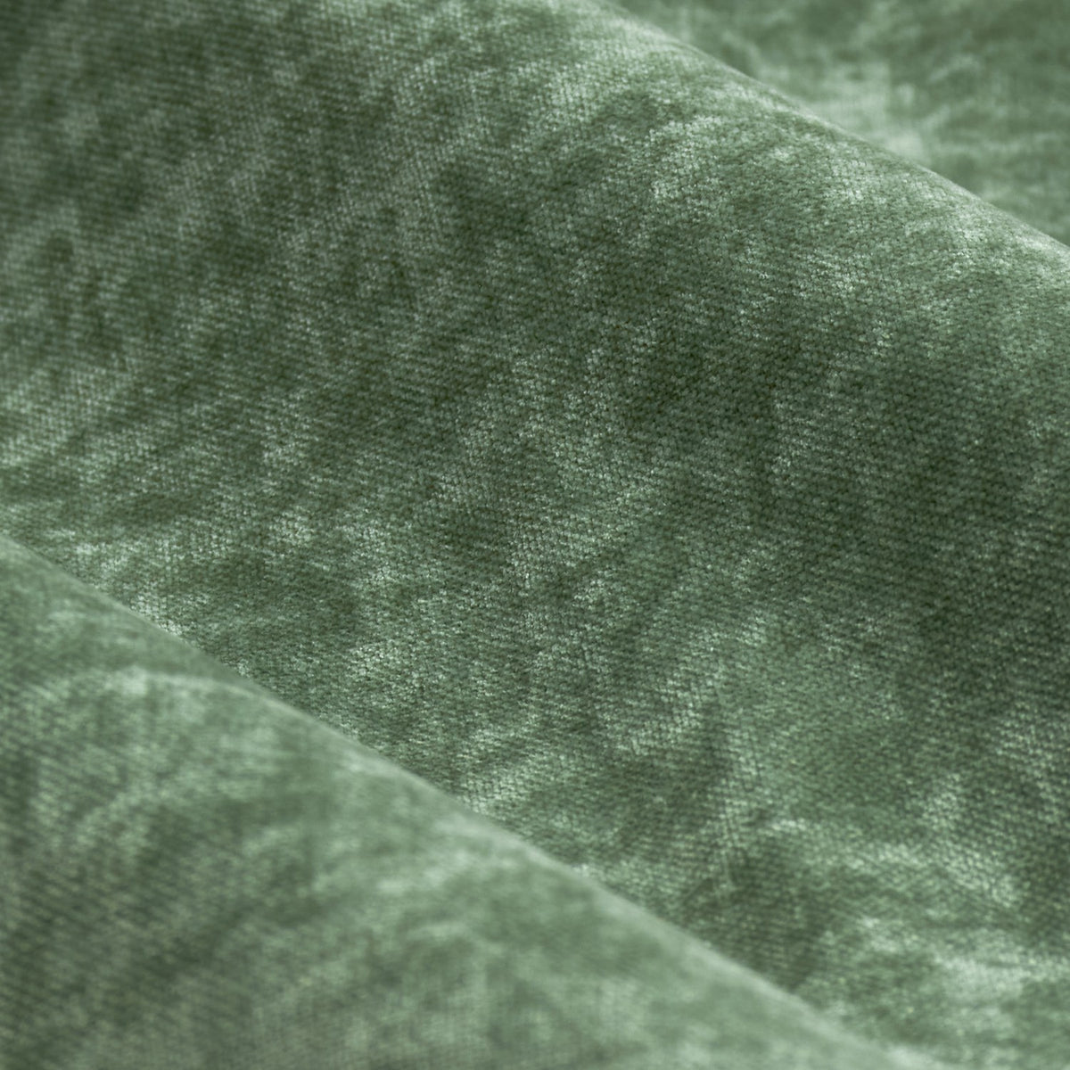 Close-up of heavy chenille velvet pencil pleat curtains in eucalyptus green, showing the dense woven texture and tonal, light-catching folds of the fabric.