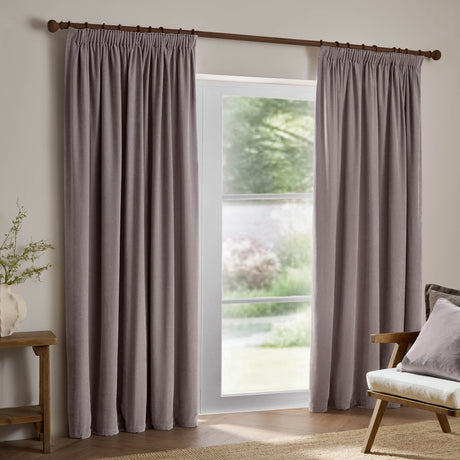 Mauve chenille velvet pencil pleat curtains with pinch-pleat heading hung on a wooden pole either side of a glazed door in a living room setting.