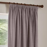 Mauve chenille velvet pencil pleat curtain hanging on a wooden pole beside a window, showing plush texture and neat gathered folds.