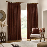 Nutmeg-red pencil pleat curtains in heavy chenille velvet fabric, hung from a wooden pole in a living room beside a patio door.