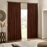 Nutmeg-red velvet chenille pencil pleat curtains hanging from a wooden pole beside a window in a living room with a mirror, side table, and rug.