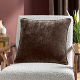 Brown Heavy Chenille Velvet Cushion with square shape and short pile finish, shown on a boucle armchair in a living room setting.
