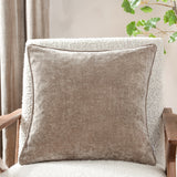 Square greige chenille velvet cushion with piped edge trim, shown on a cream boucle armchair in a living room setting.