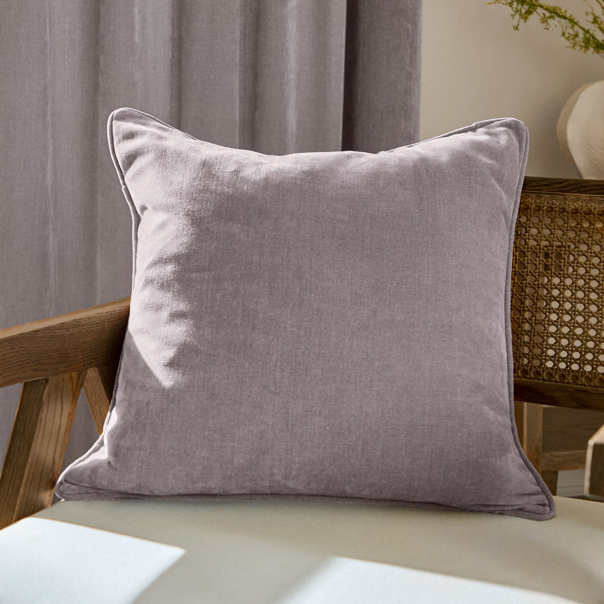 Heavy Chenille Plain Velvet Cushion in mauve with flanged edge, 50 x 50cm, shown propped against a wooden chair in a living room setting.