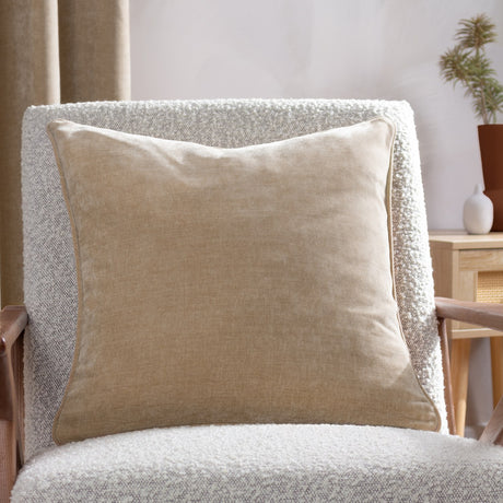 Square natural cream chenille velvet cushion with piped edge, shown on a white bouclé armchair in a living room setting.