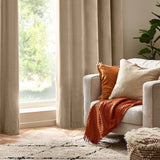 Natural cream Heavy Chenille Eyelet Velvet Cushion with fringed edge, styled on a light grey armchair alongside an orange throw and cushion in a living room setting.