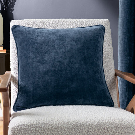 Heavy Chenille Eyelet Velvet Cushion in navy, a square 50 x 50cm scatter cushion with piped edge trim, shown on a boucle armchair in a living room setting.