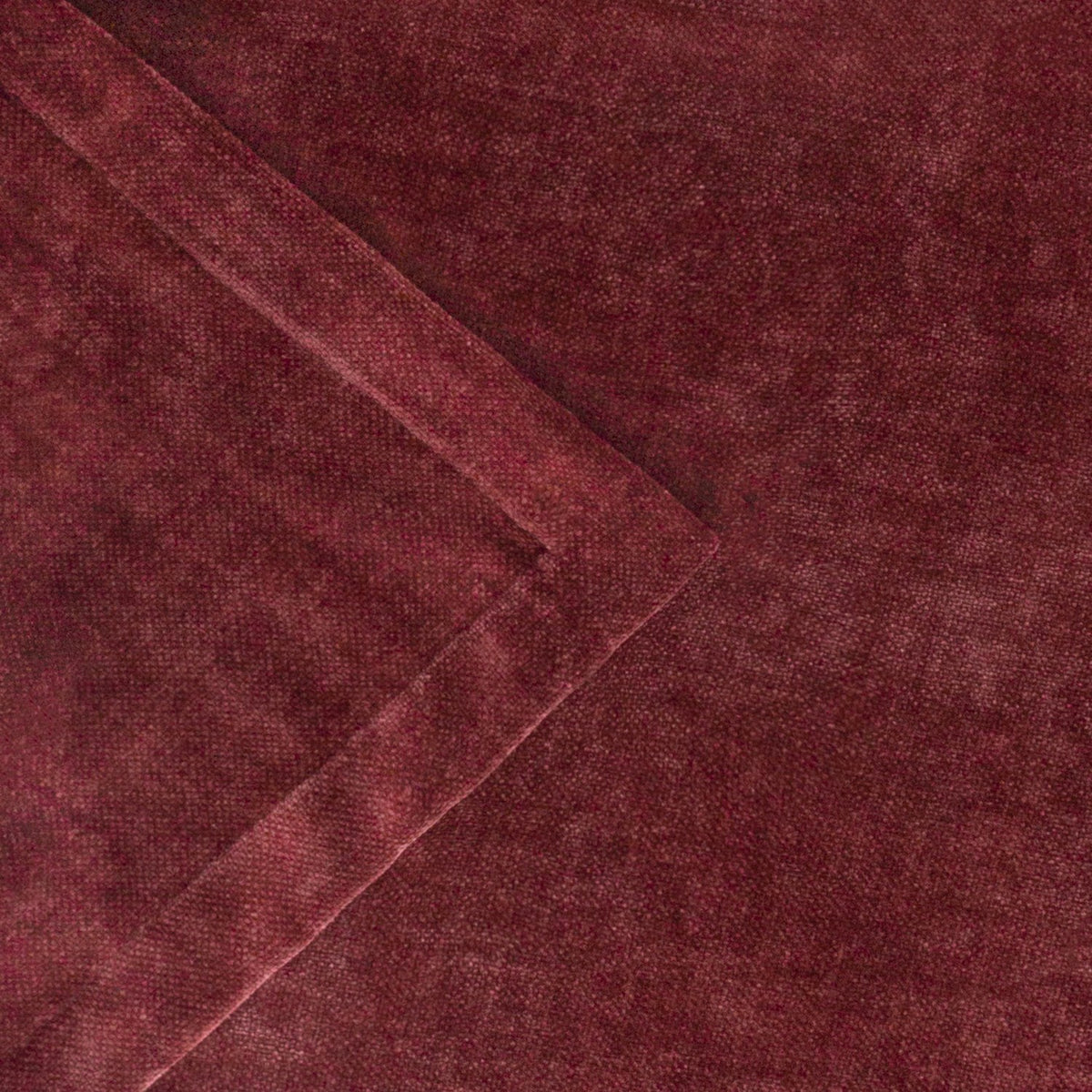 Close-up of a heavy chenille velvet throw in deep beetroot red, showing a folded corner with hemmed edge and the mottled, wine-toned pile texture.