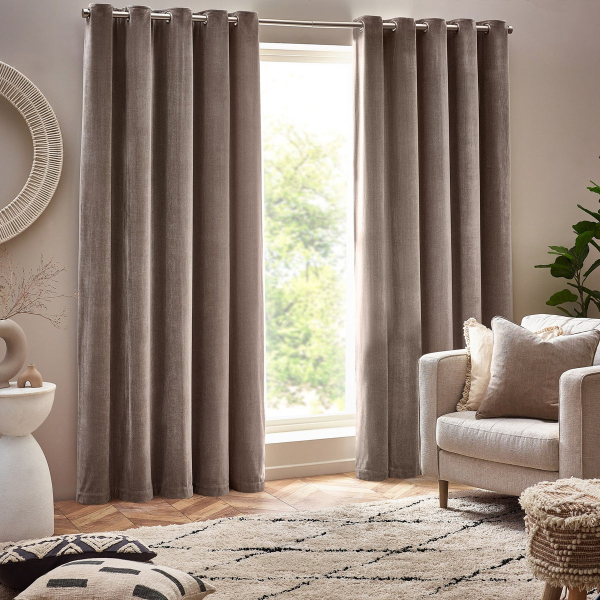 Heavy Chenille Velvet Plain Eyelet Curtains in greige, hung floor-length either side of a window with grommet header, shown in a living room beside an armchair.