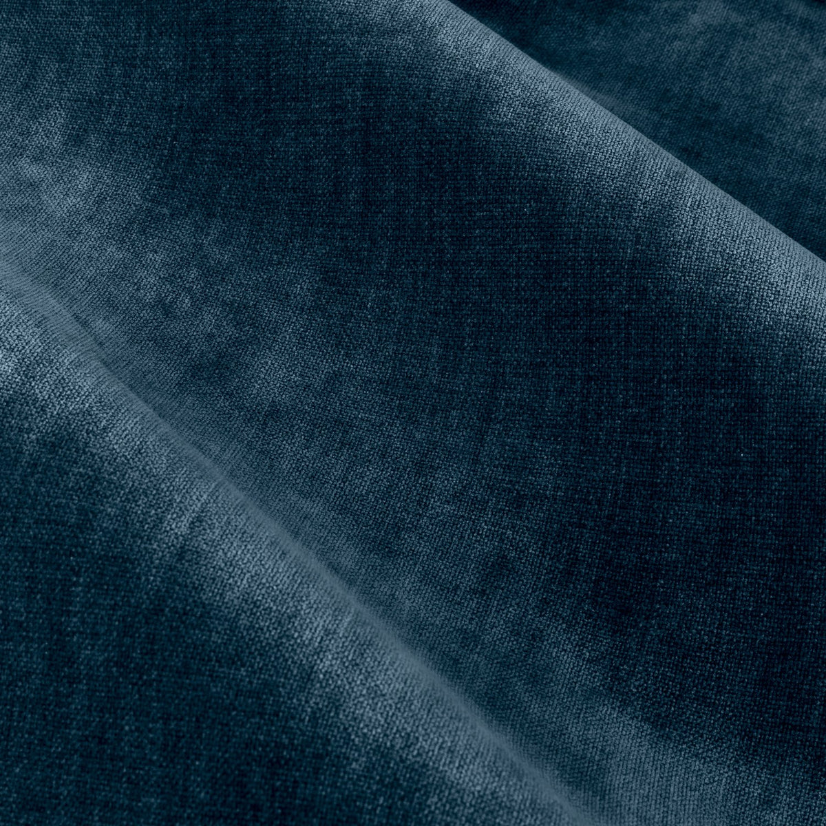 Close-up of heavy chenille velvet eyelet curtain fabric in deep navy blue, showing soft rounded folds and light catching the pile texture.