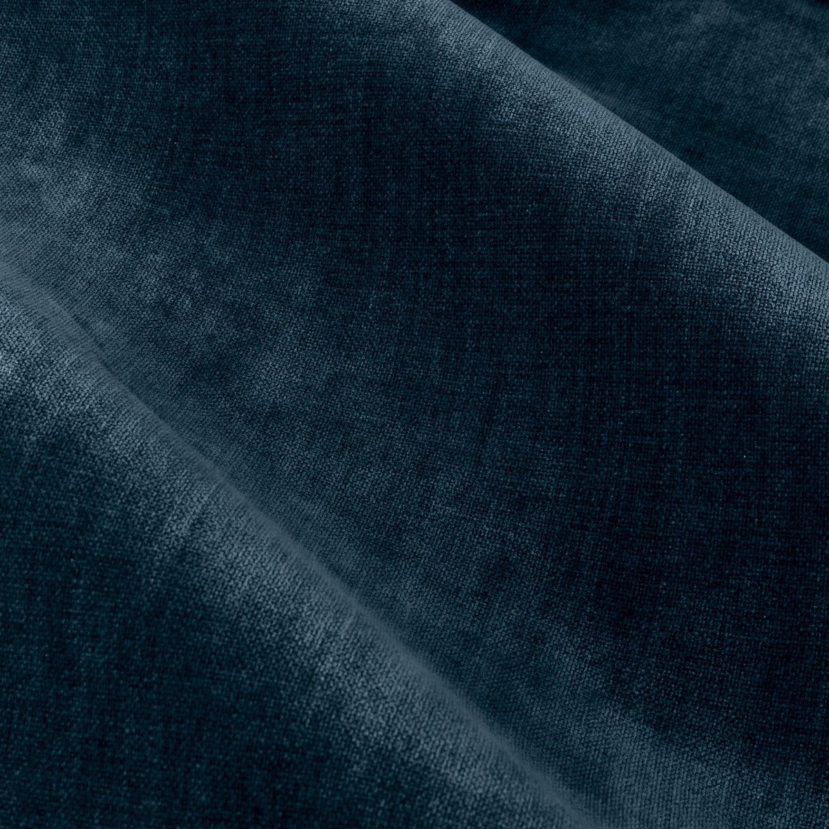 Close-up of heavy chenille velvet pencil pleat curtain fabric in deep navy blue, showing a dense plush pile with soft, uneven light reflection and draped folds.