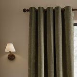 Heath Washed Velvet Fully Lined Eyelet Curtains in Eucalyptus, textured green velvet panels on a dark eyelet rod, styled beside a wall-mounted lamp with linen shade.