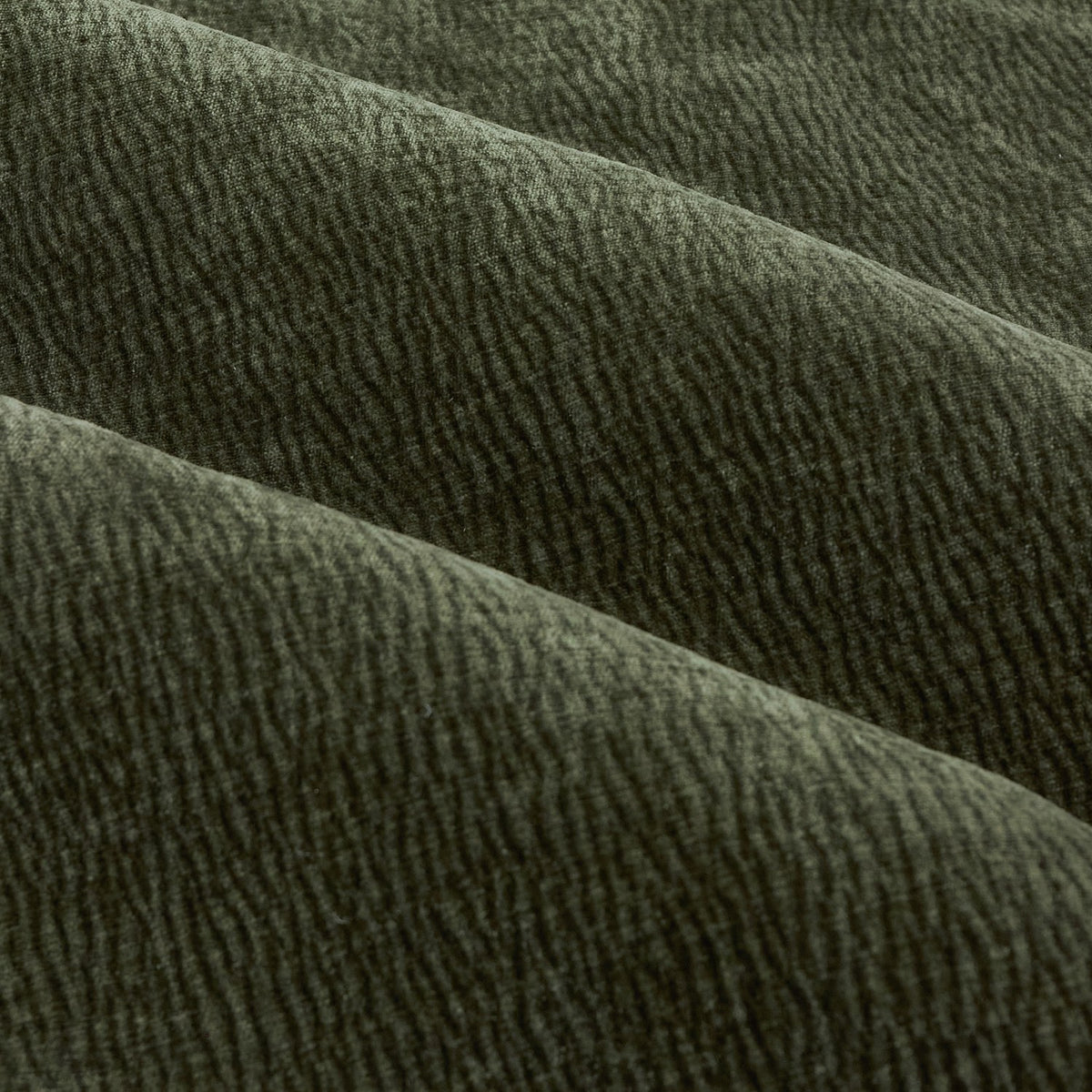 Close-up of Heath eyelet curtain fabric in olive green, showing enzyme-washed velvet with a subtle jacquard weave and soft, irregular textured pile.