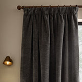 Heath Washed Velvet Pencil Pleat Curtains in charcoal grey, shown hung on a bronze pole with pencil pleat heading, textured pile visible in a living room setting.